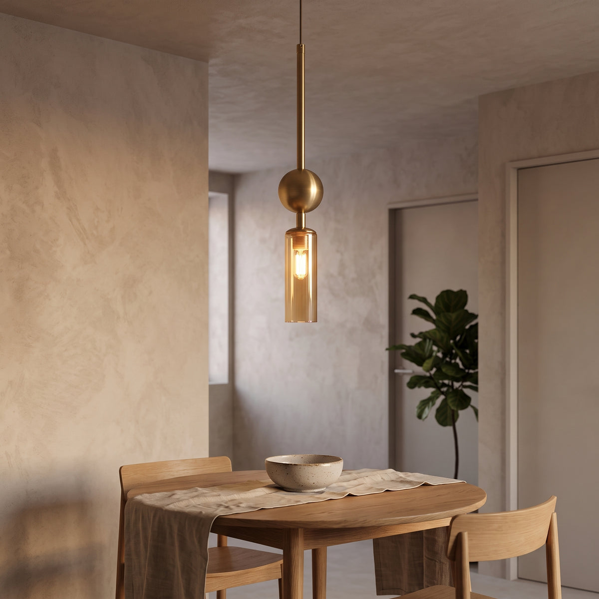 Brass pendant light with amber glass tube above an oak dining table