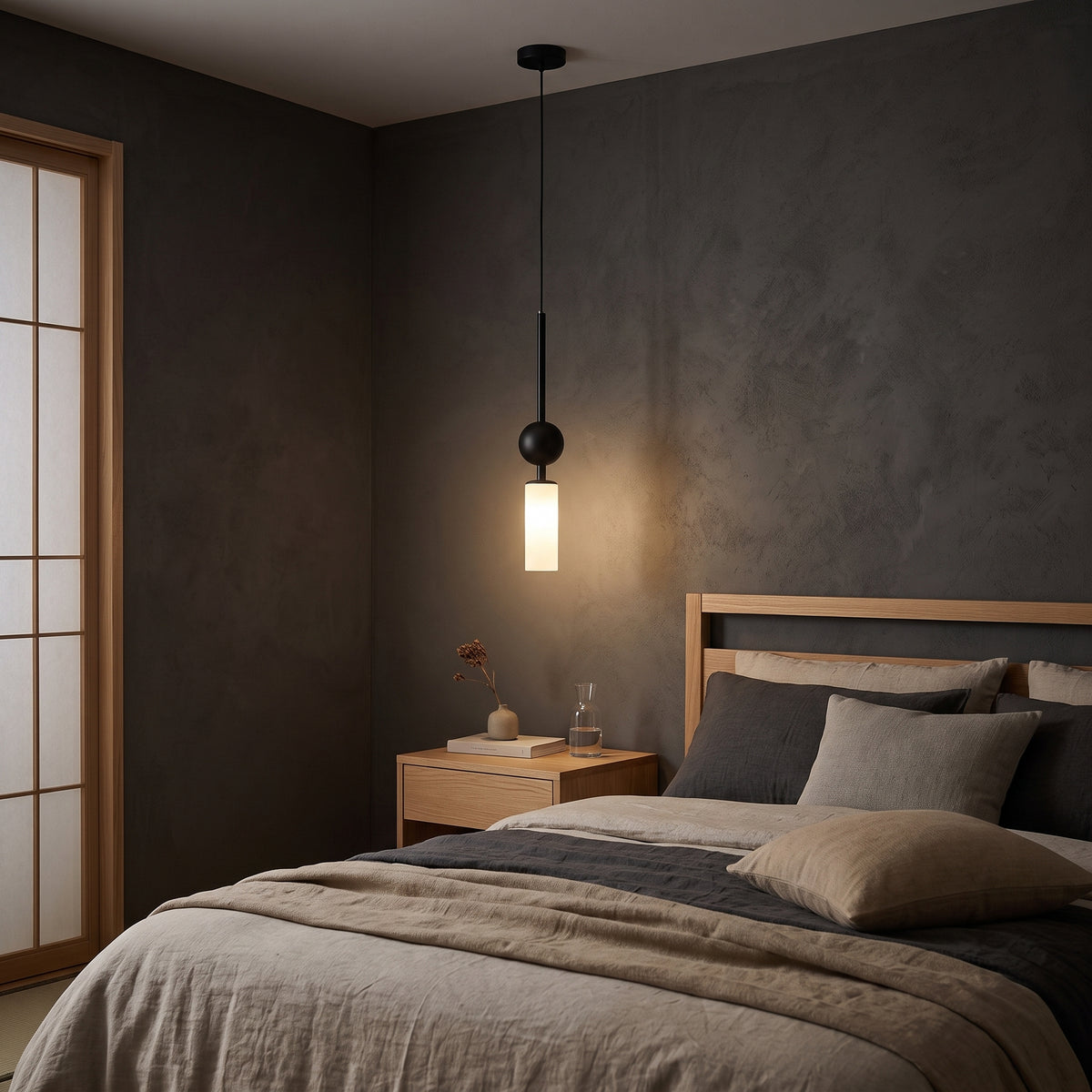 Black pendant light with milk white glass tube beside a Japandi bed