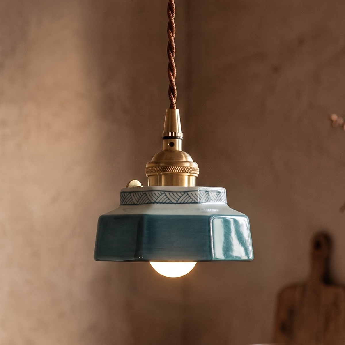 Teal glazed ceramic mini pendant with brass socket over a kitchen counter