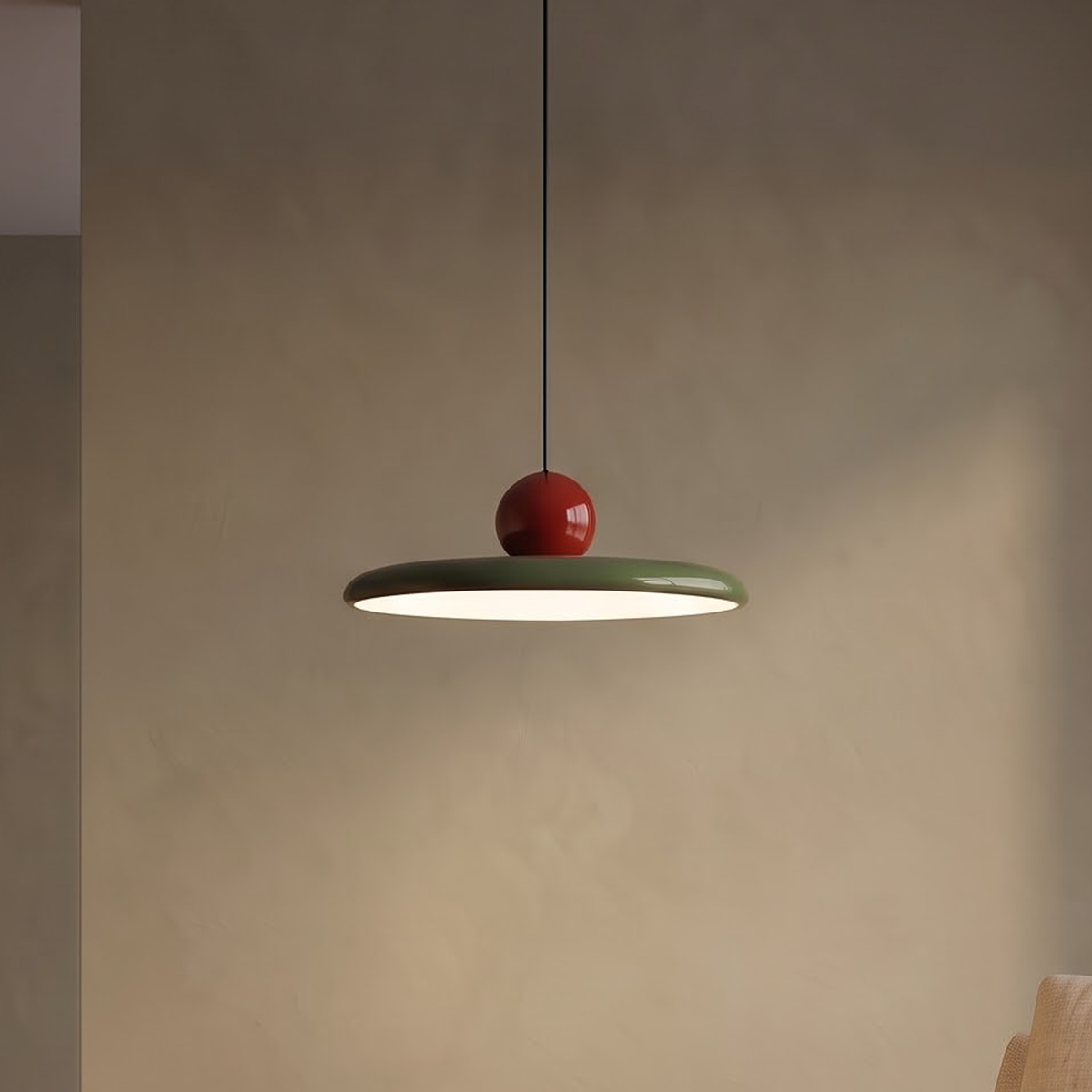 Sage green saucer pendant with red ball glowing over an oak table