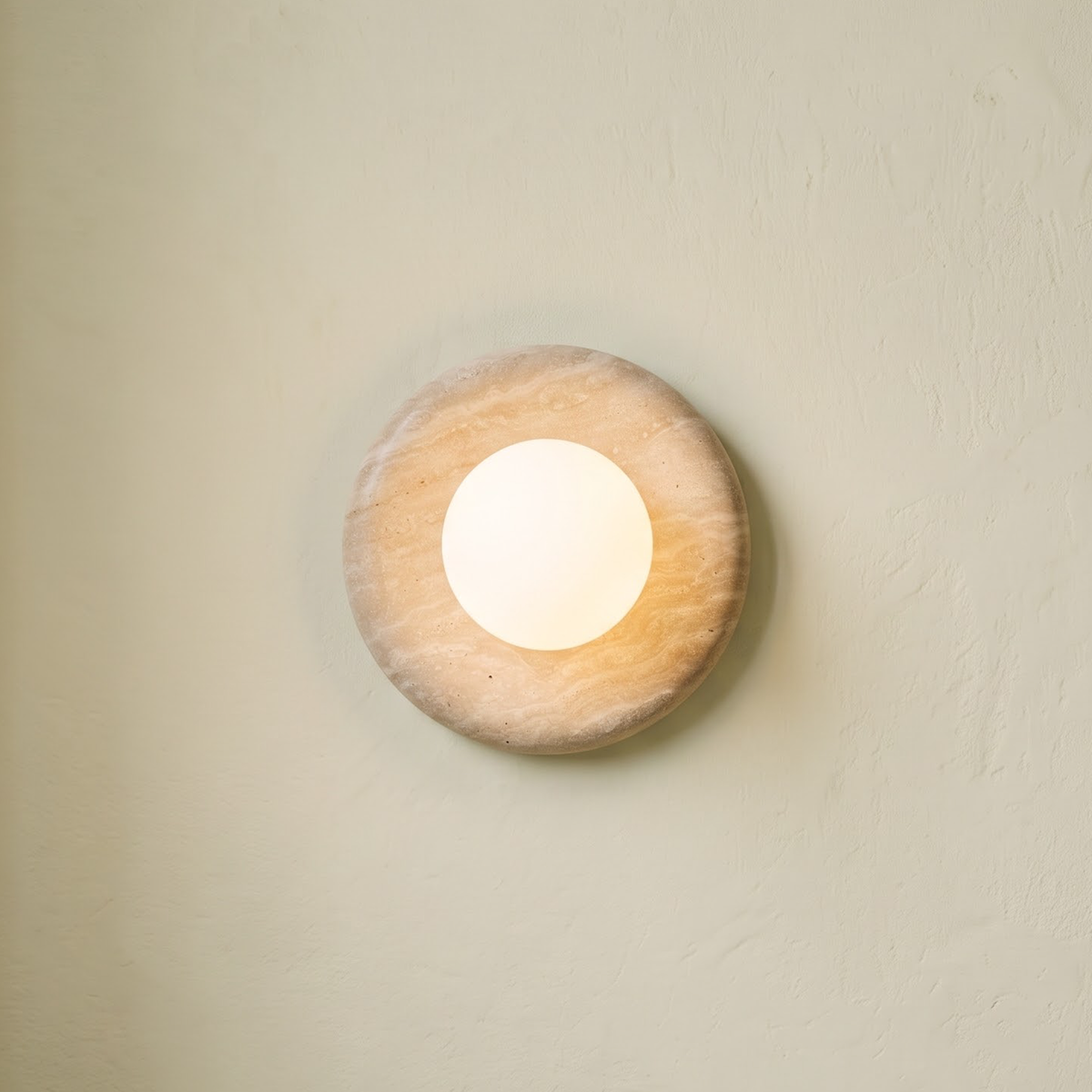 Sand stone disc wall light with glowing glass ball in a hallway