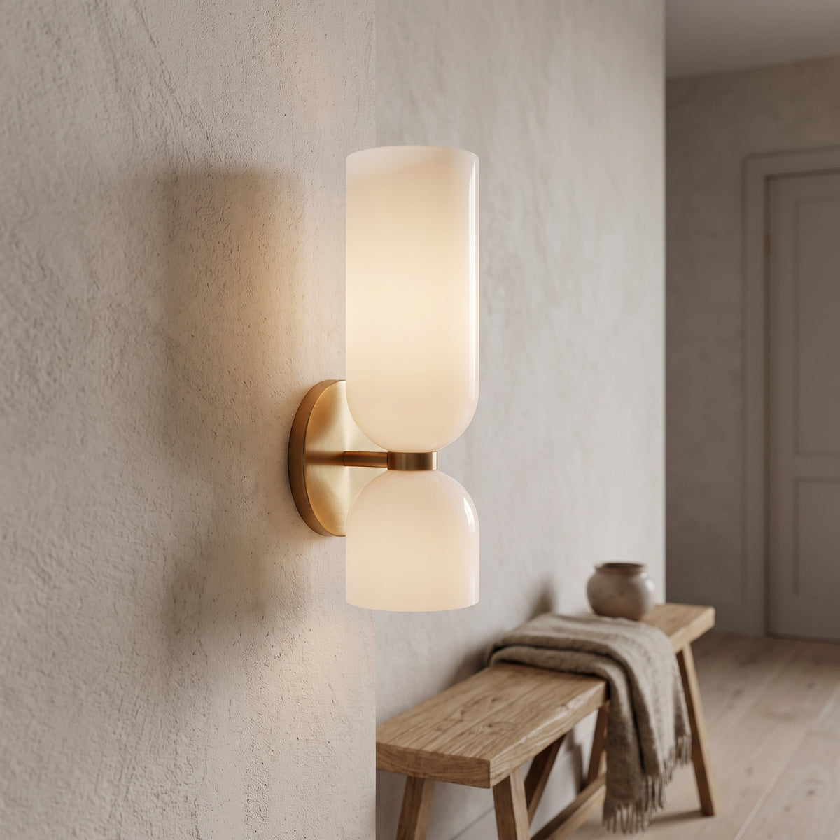 White opal glass wall sconce with brass plate in an entry hallway