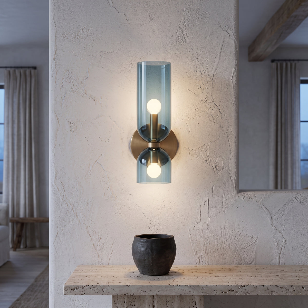 Blue glass wall sconce above a travertine console at blue hour