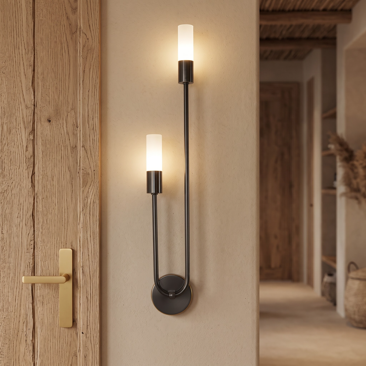 Black twin-tube wall sconce glowing beside an oak door frame