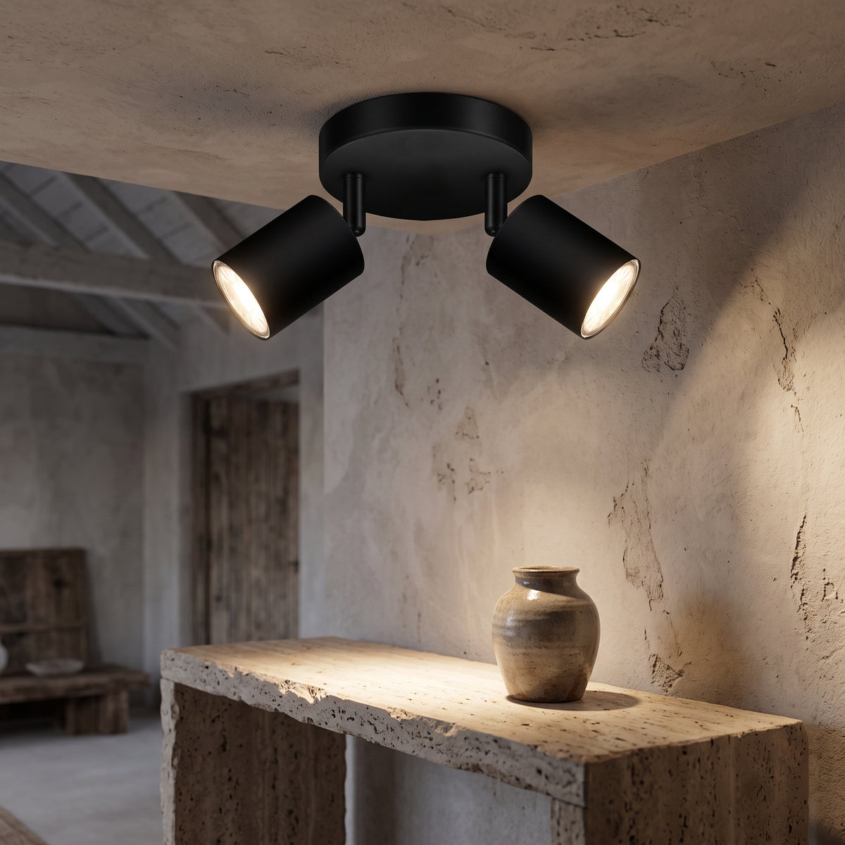 Black two-light ceiling spotlight over a travertine console