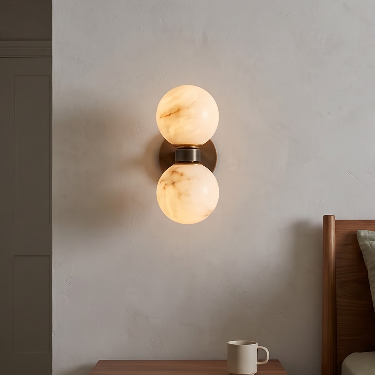 Double marble globe wall sconce glowing warm beside an oak door