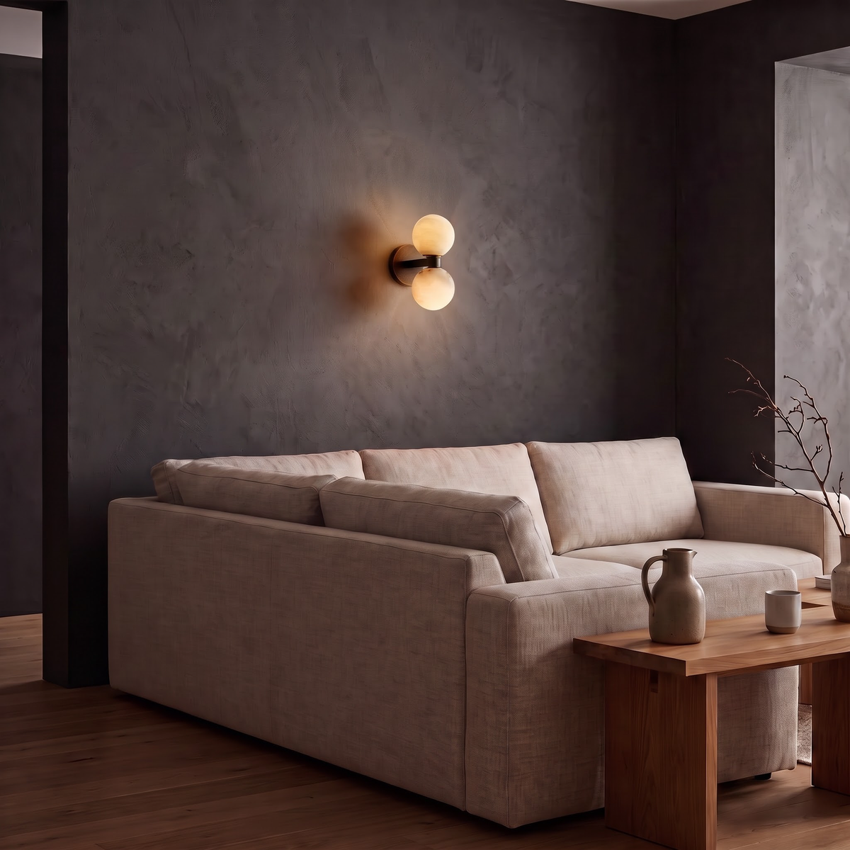 Marble globe wall light glowing on a dark plaster wall above a sofa