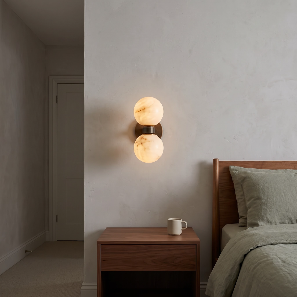 Marble double globe sconce above a walnut nightstand in a calm bedroom