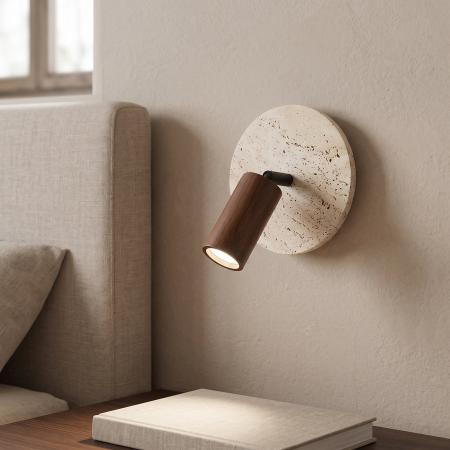 Travertine disc wall reading light with walnut spotlight beside a bed