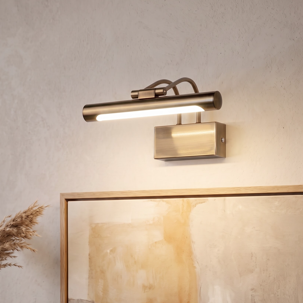 Brass-bronze picture light glowing above an oak-framed abstract painting