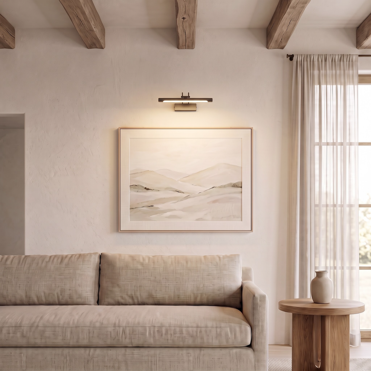 Brass picture light above a landscape painting over a linen sofa