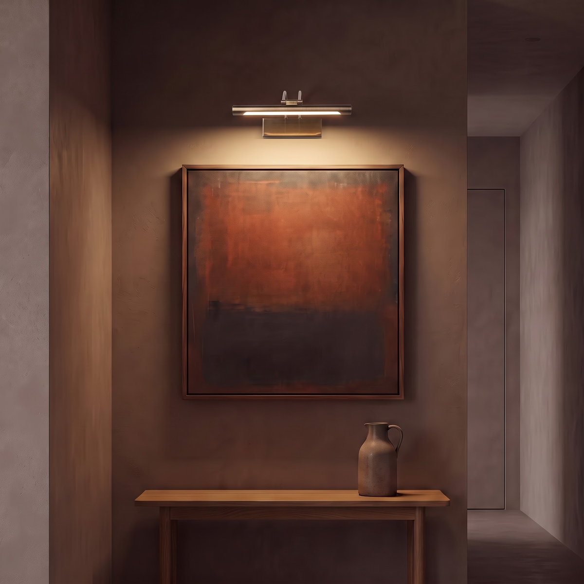 Picture light washing warm light over a painting in a dark hallway