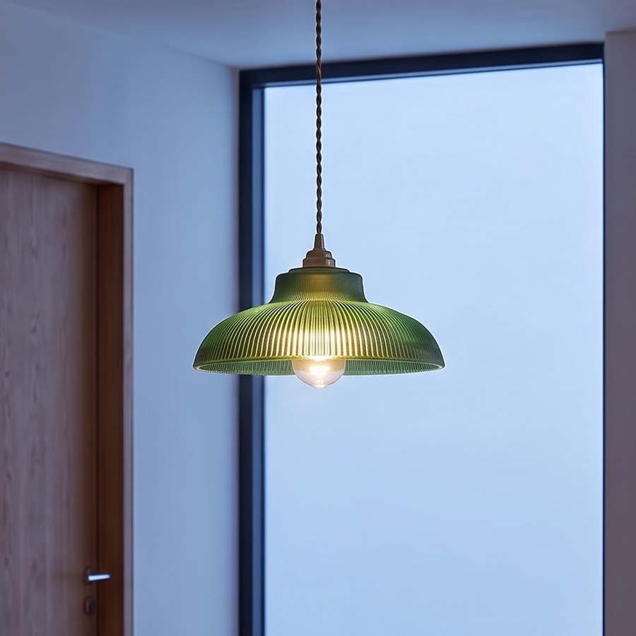 Green ribbed glass pendant light glowing over an oak dining table