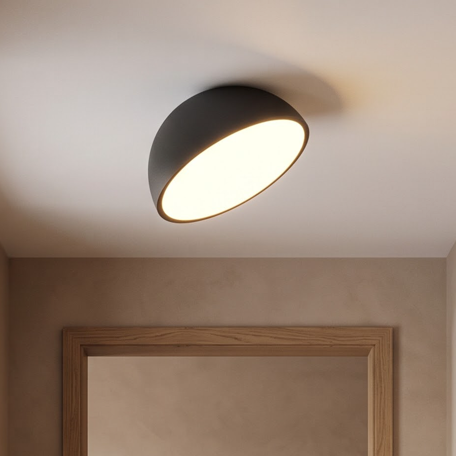 Black tilted dome flush ceiling light glowing in a plaster hallway