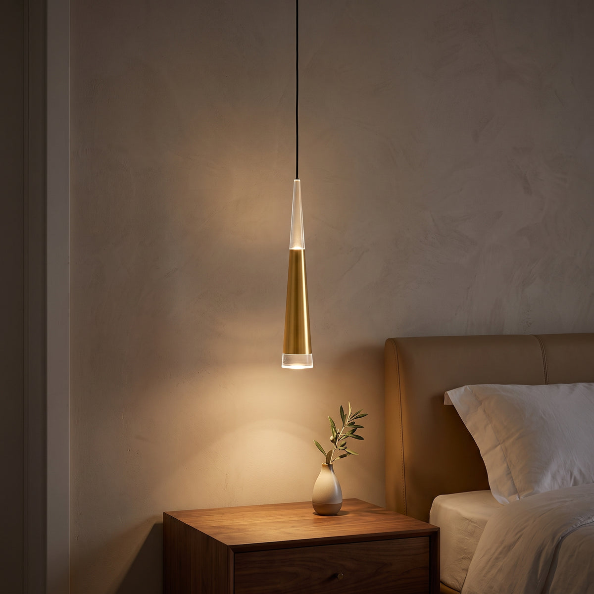 Slim gold cone mini pendant glowing over a walnut nightstand at night