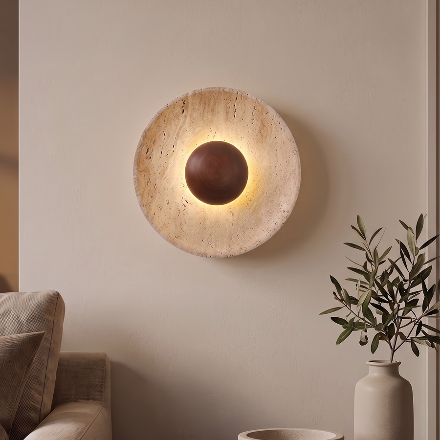 Travertine stone disc wall light with walnut ball above a linen sofa
