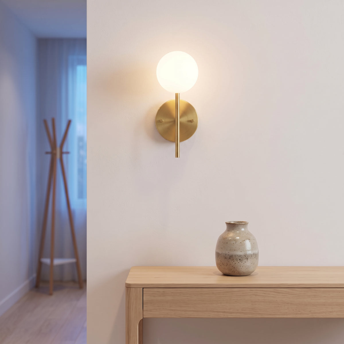 Hoshi gold globe sconce glowing above an oak console in a quiet hallway