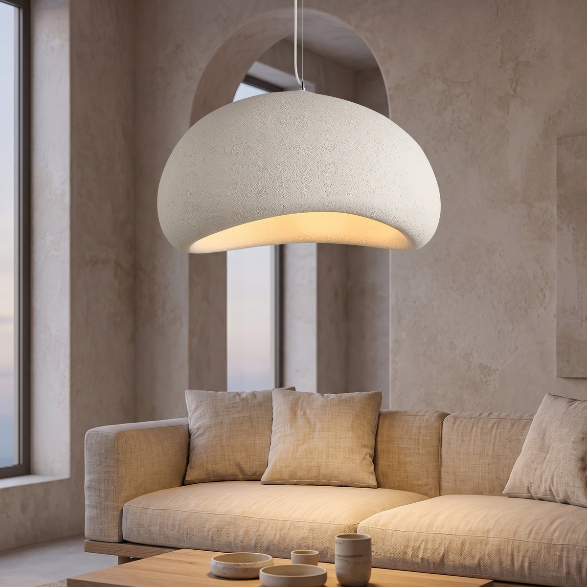 Textured wabi-sabi pendant glowing above a linen sofa at dusk