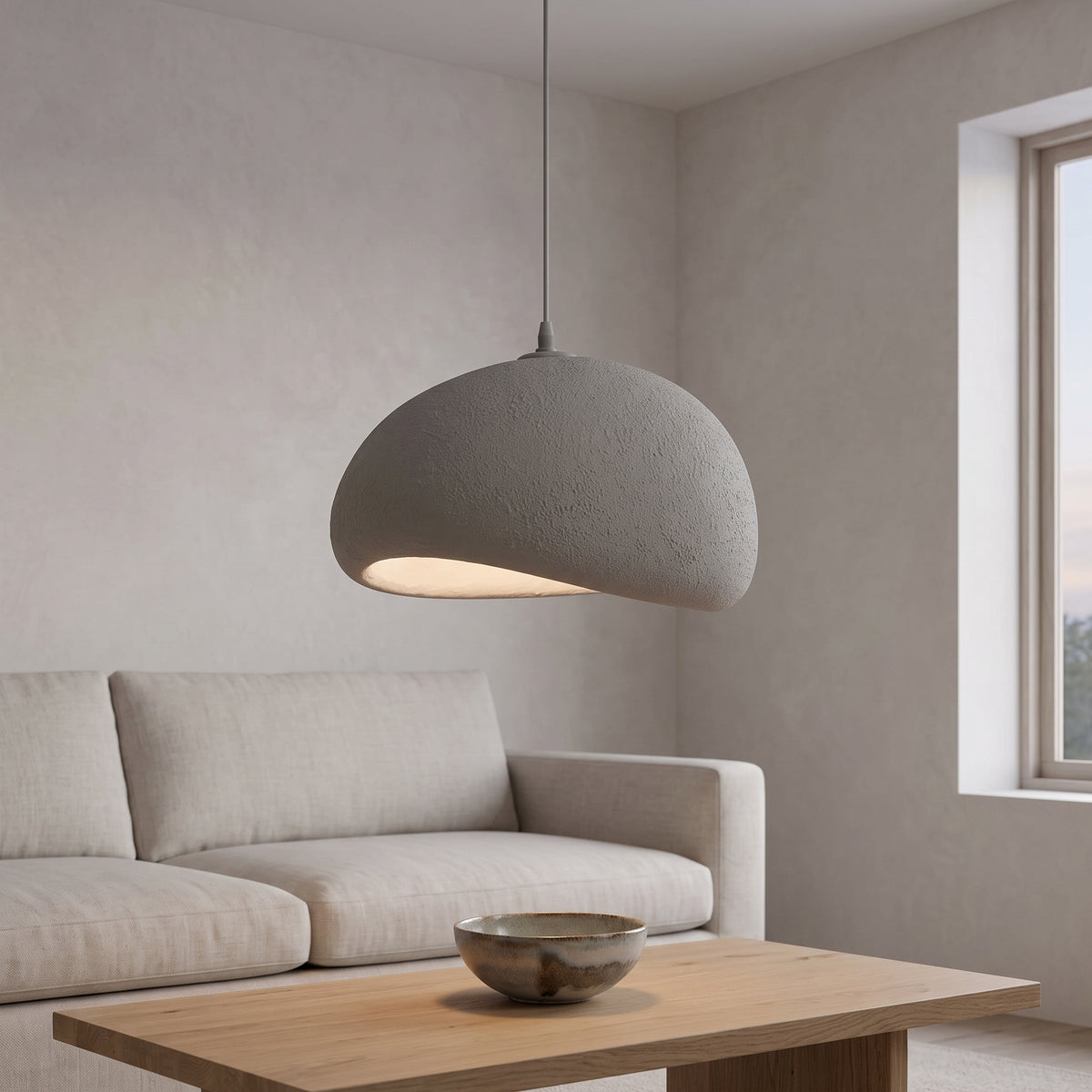 Gray textured pebble-shaped pendant light over an oak coffee table in a living room
