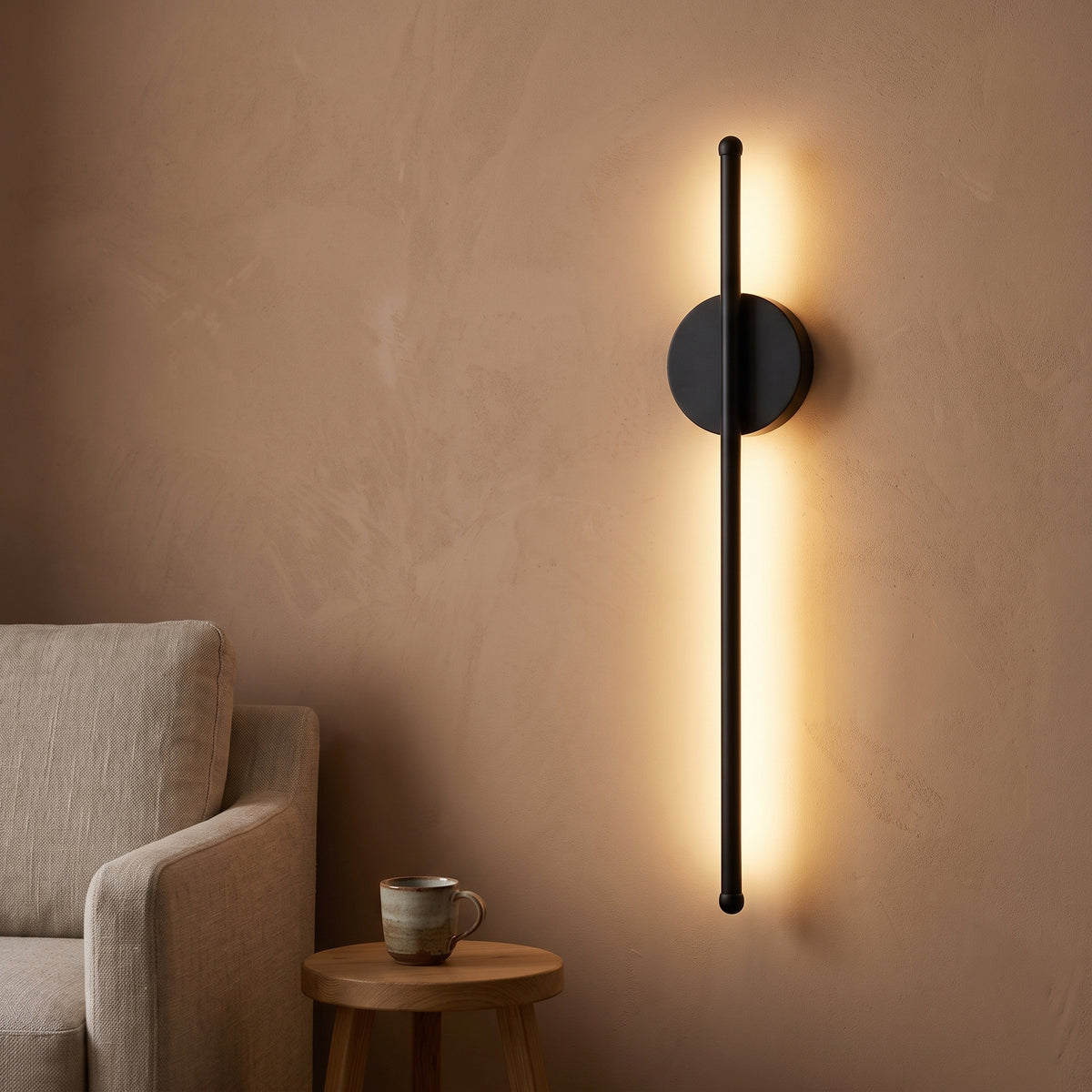 Black rod wall sconce with round disc lit in a plaster reading nook