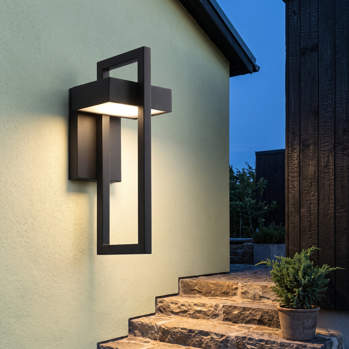 Black modern porch wall light glowing over stone steps at twilight
