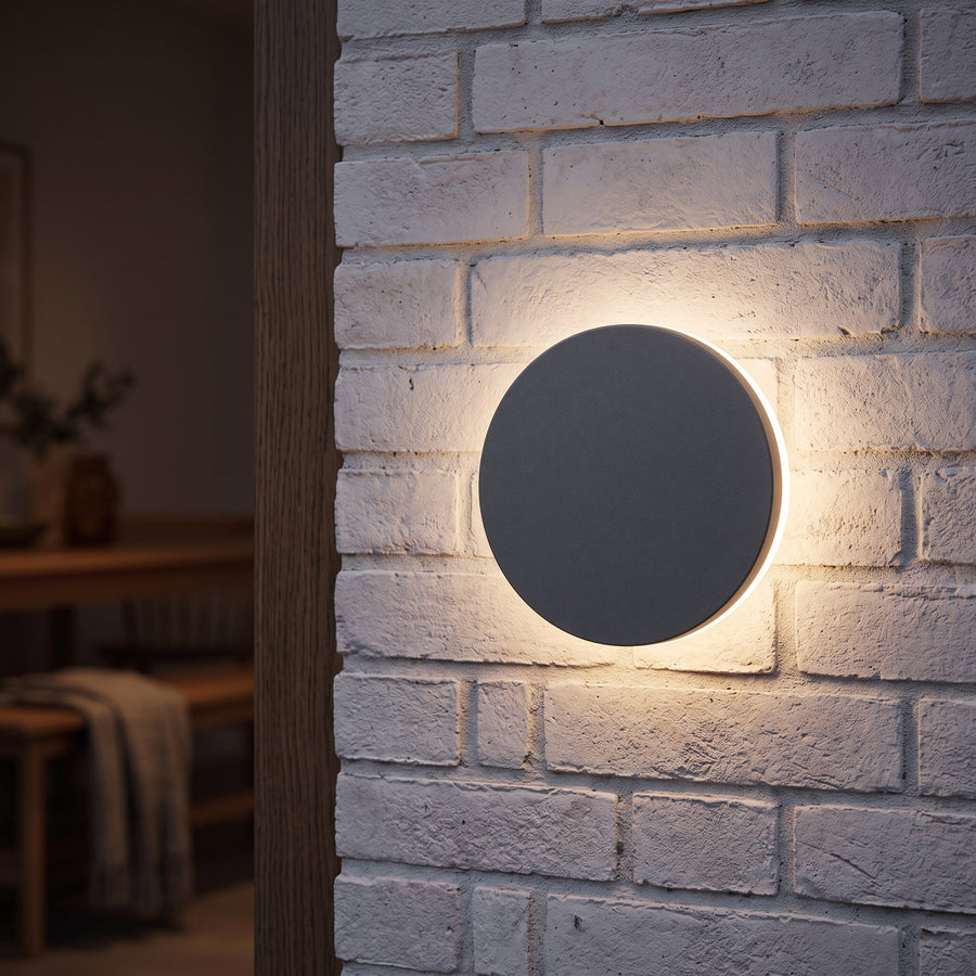 Round black halo outdoor wall light beside a modern front door at dusk