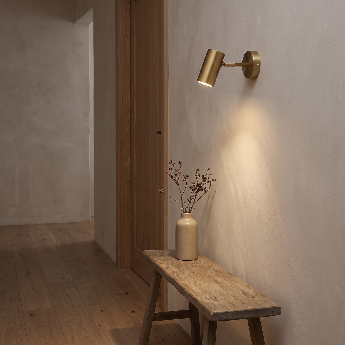 Gold compact wall spot lighting a limewashed hallway wall above an oak bench