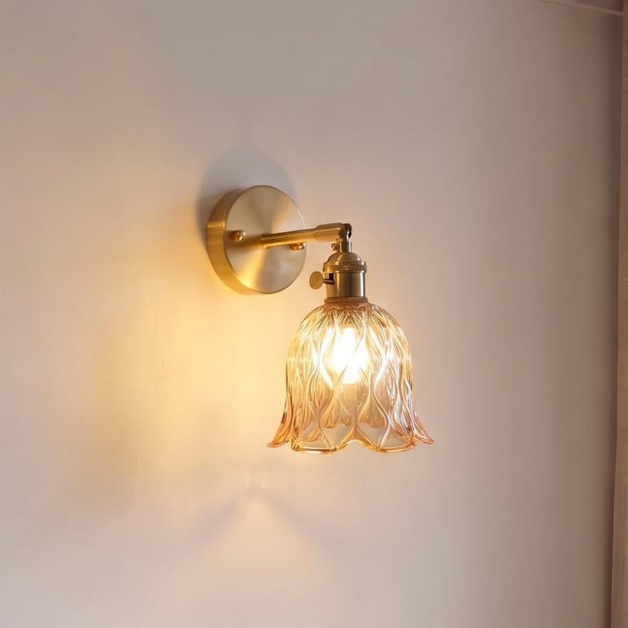 Amber glass bell wall sconce on a brass swing arm by a bed