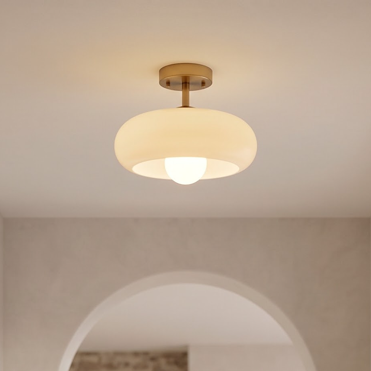 Cream glass semi-flush ceiling light glowing in an arched entry hall