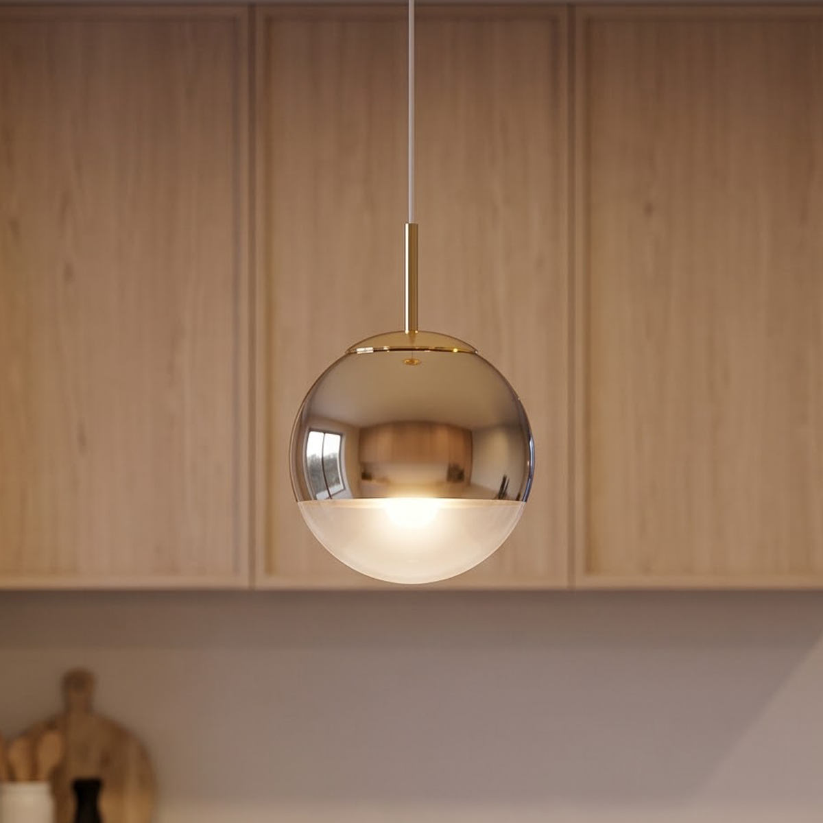 Gold mirror globe pendant glowing above a limestone kitchen island