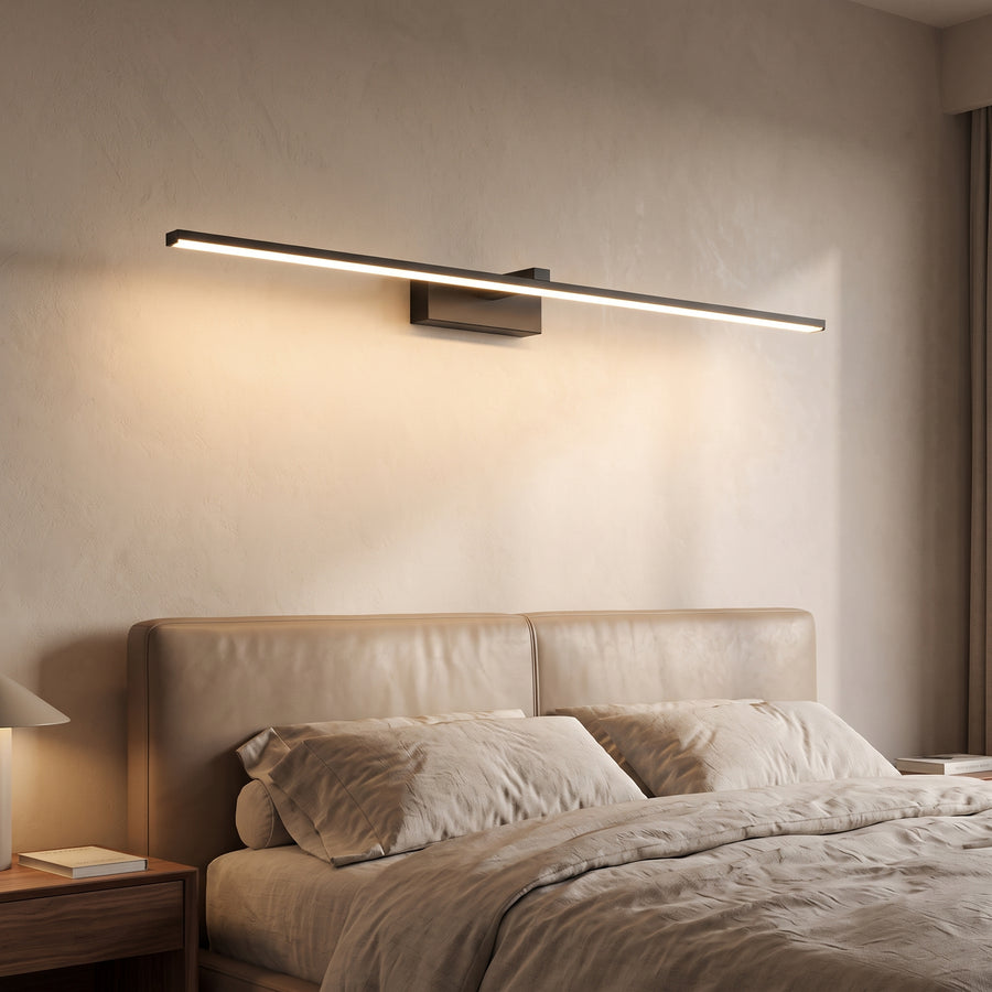 Black linear LED wall sconce above a bed on a plaster wall