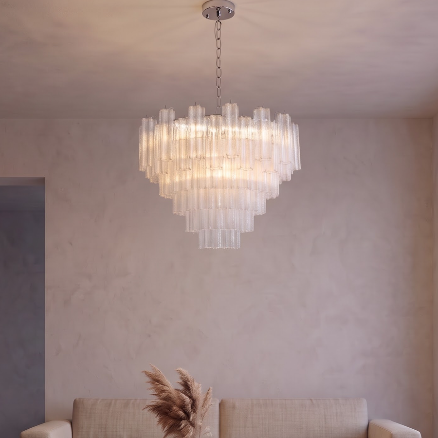 Tiered clear glass tube chandelier glowing above a walnut dining table