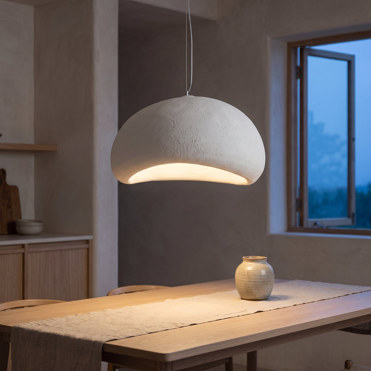 White smooth dome pendant light above an oak dining table at dusk