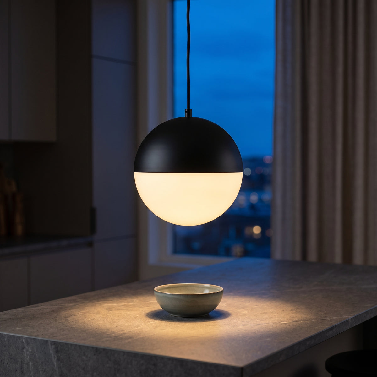 Black dome opal glass pendant above a stone kitchen island
