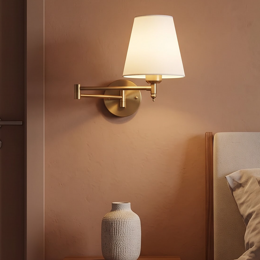 Brass folding swing-arm wall lamp with white shade beside a bed