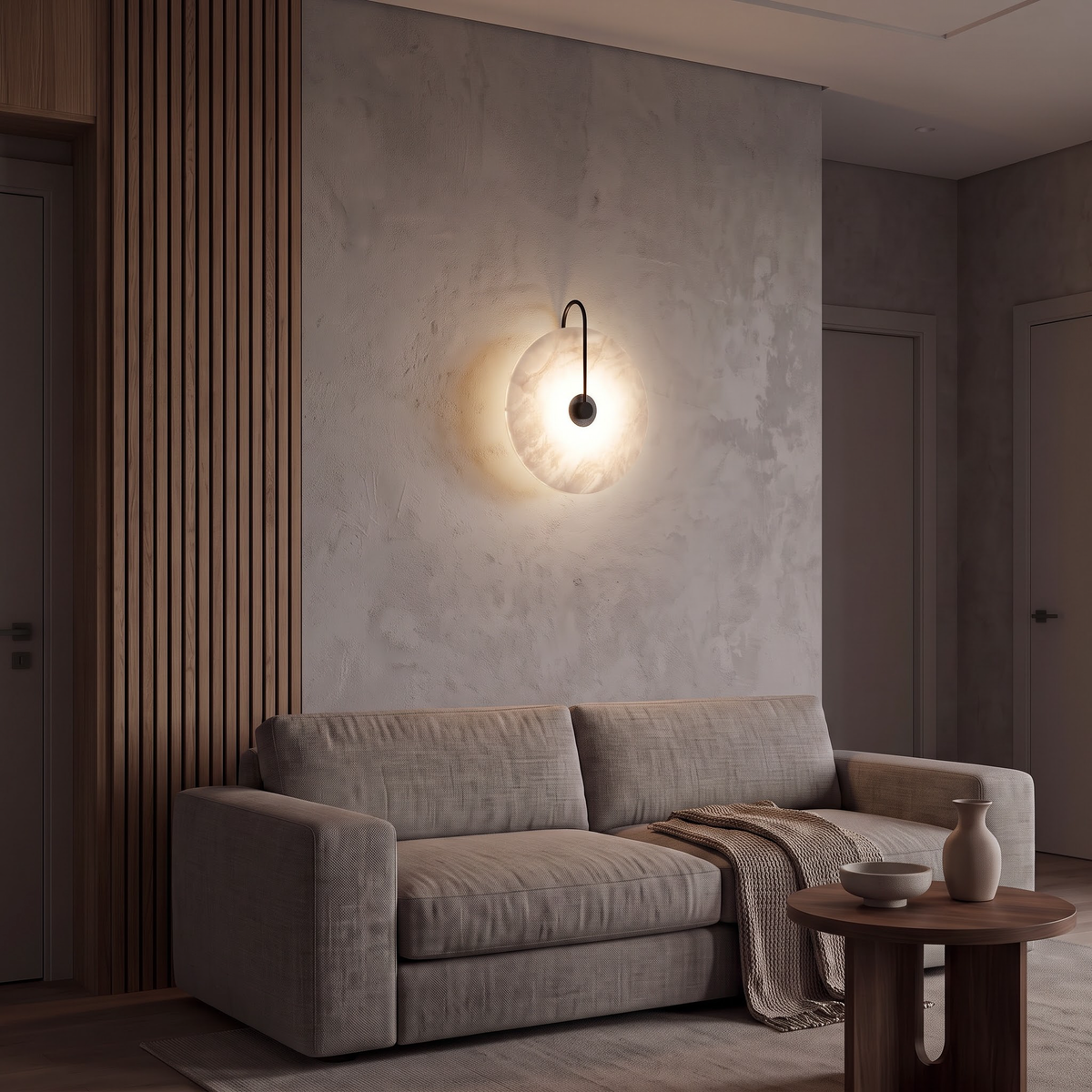 Large marble disc wall light above a low linen sofa at night
