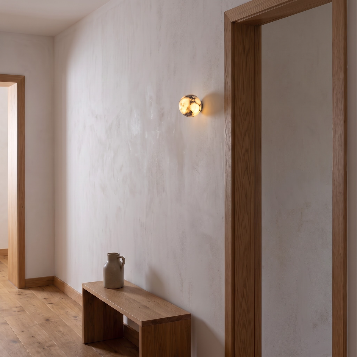 Small marble ball wall light glowing beside an oak door frame