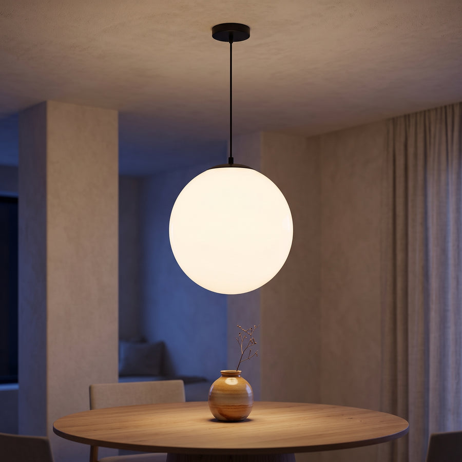 Opal glass globe pendant with black cord over an oak dining table