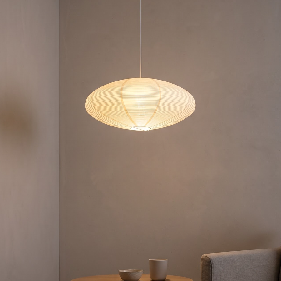 Ribbed paper lantern pendant glowing over an oak dining table
