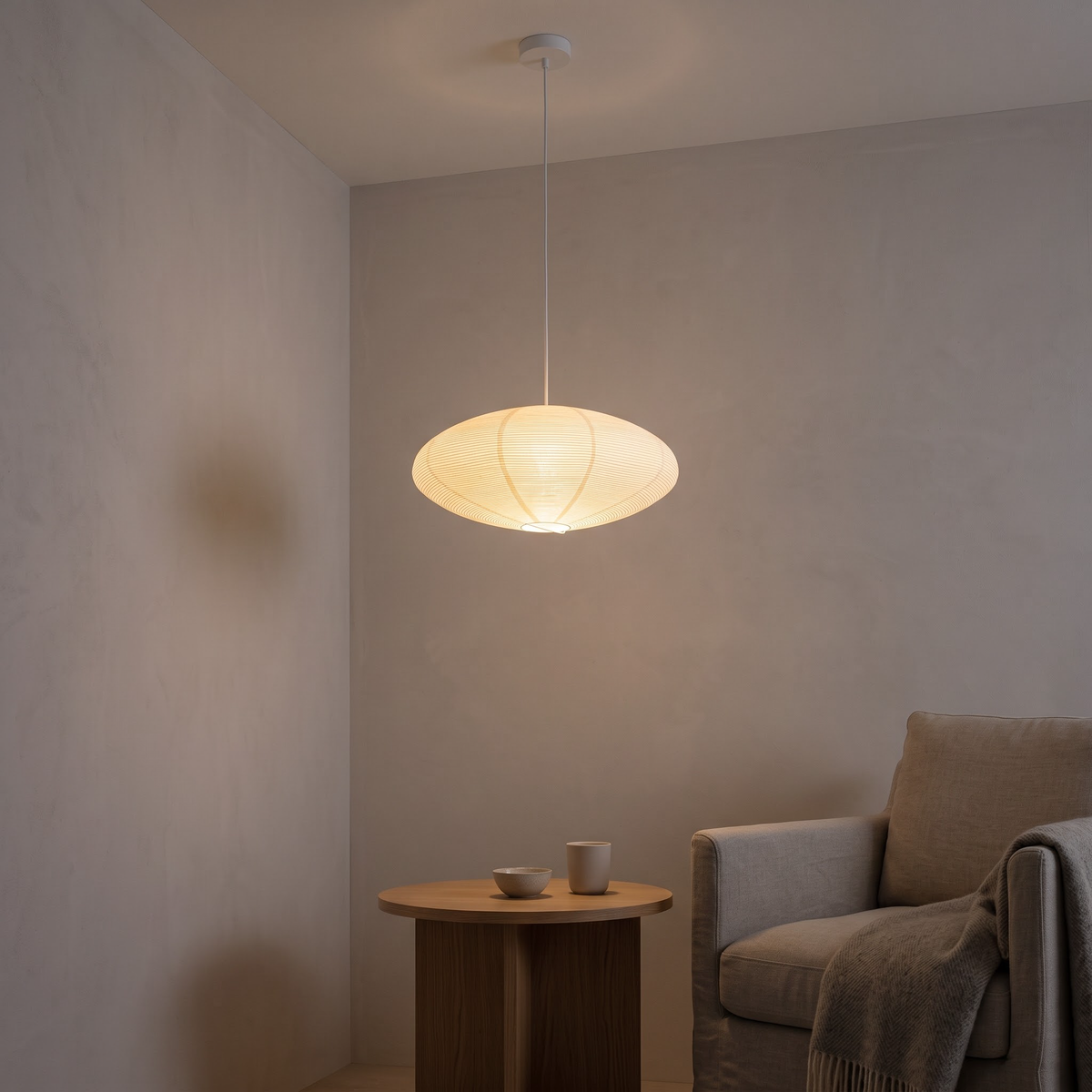 Paper disc pendant lamp glowing beside a linen reading chair