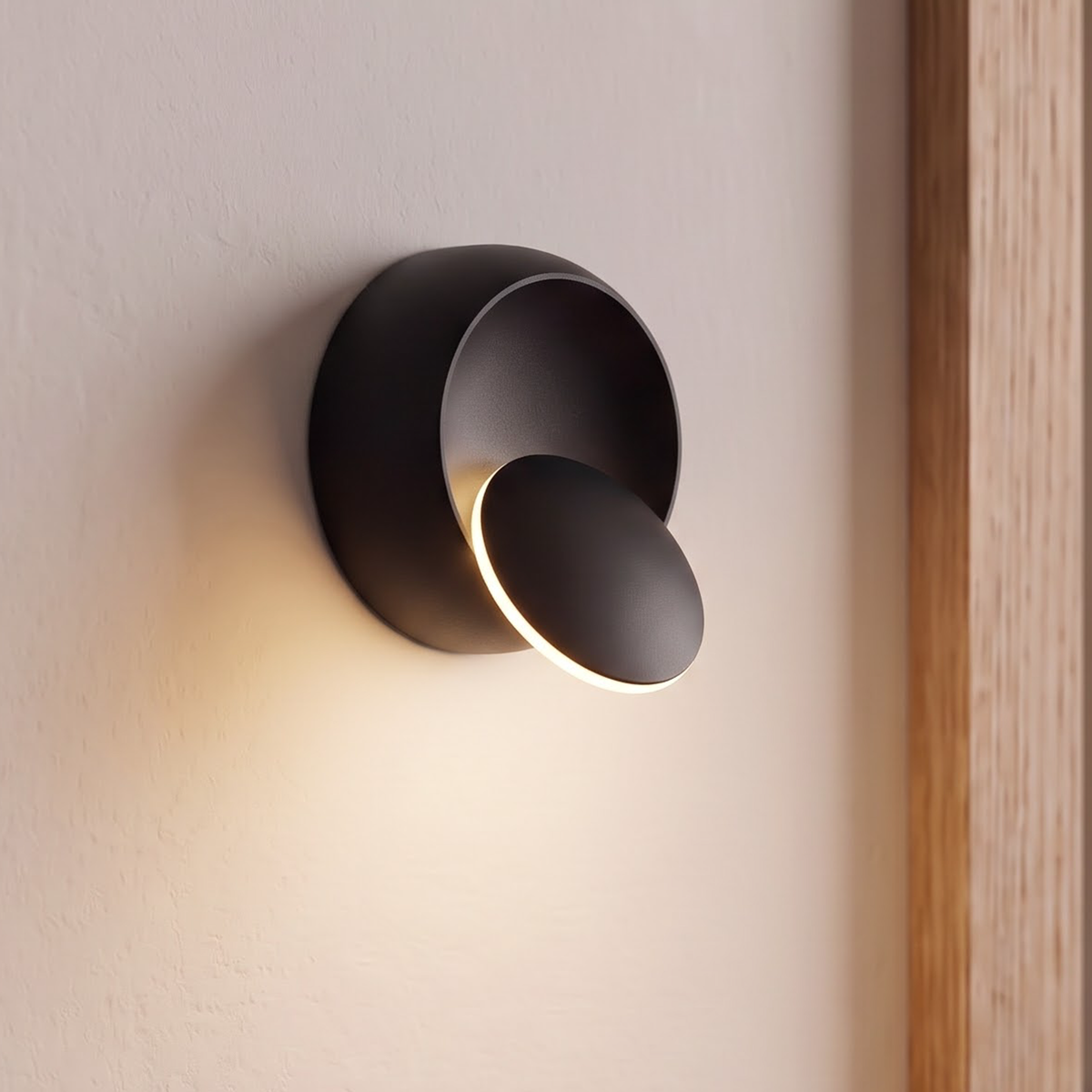 Small matte black round wall light with swivel disc beside a door