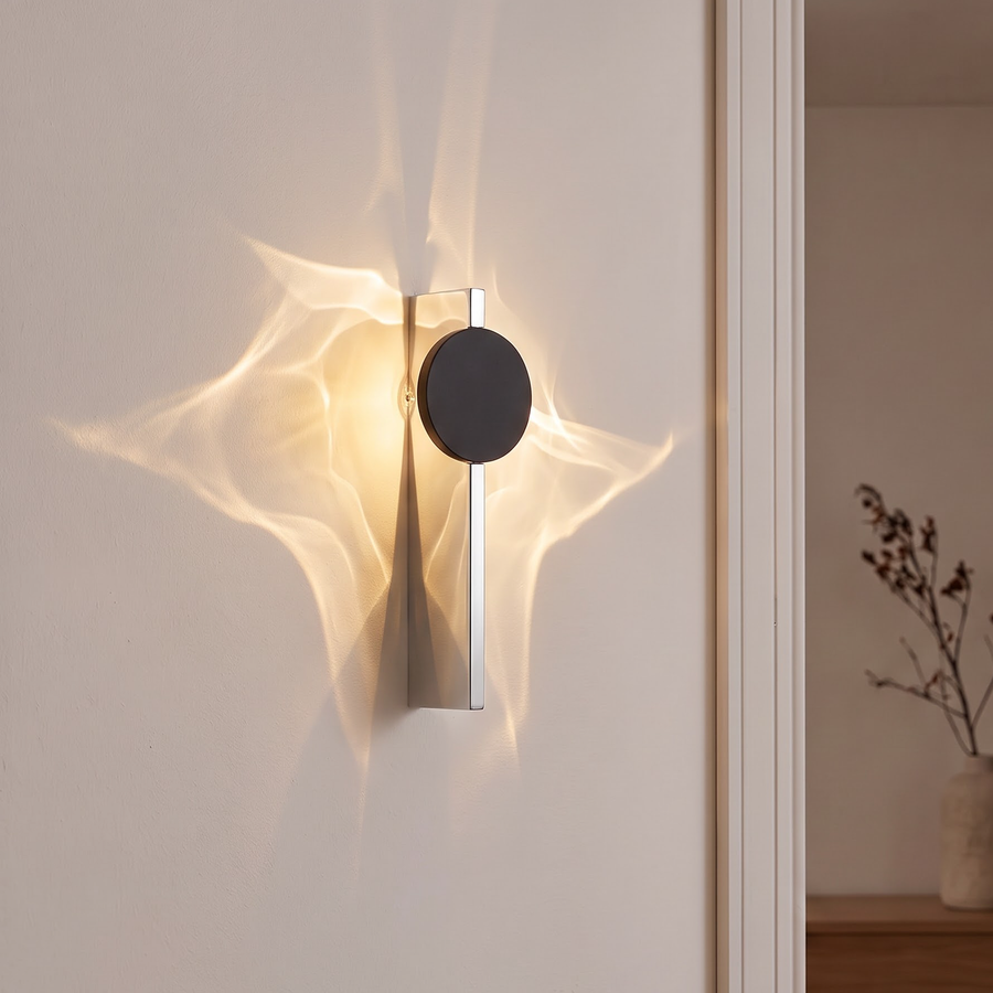 Chrome and black disc wall light casting rippled light on a wall