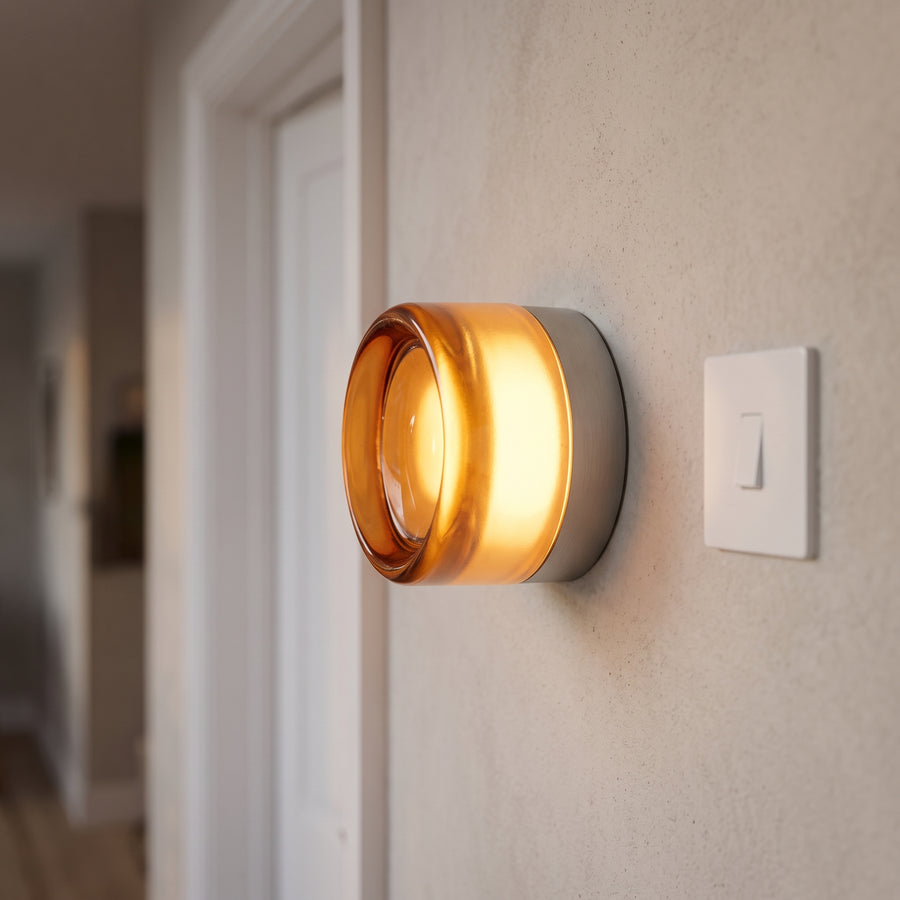 Amber puck wall light glowing on a limewashed plaster wall