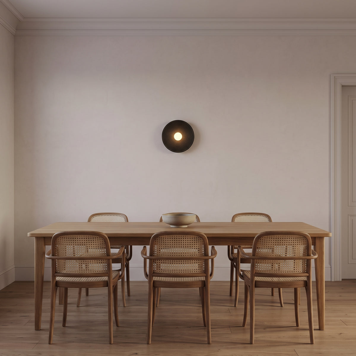 Matte black ribbed disc wall light above an oak dining table