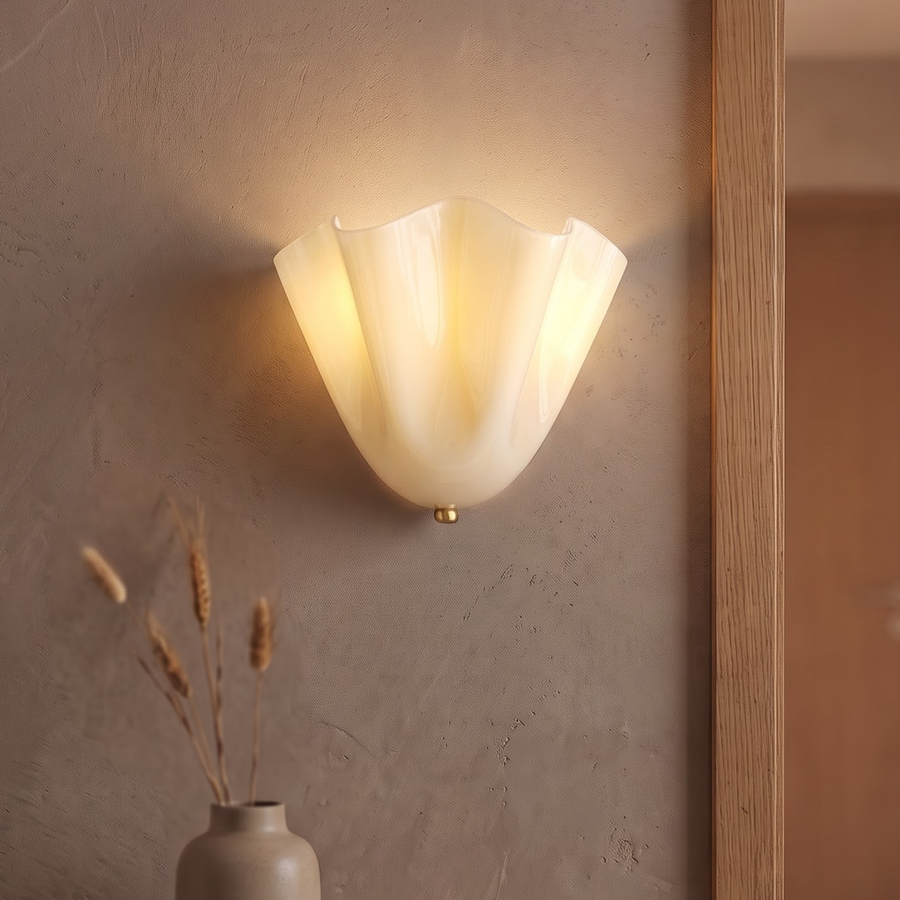 Cream rippled glass flower wall sconce glowing beside a doorway