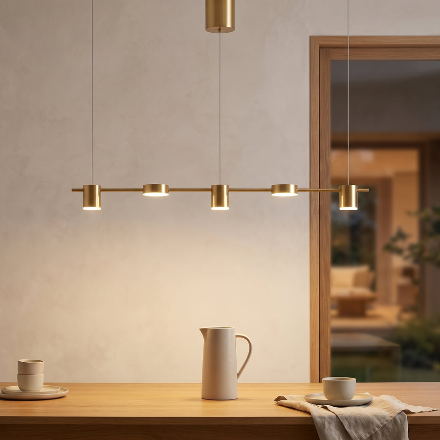 Brushed gold five-light linear pendant glowing over an oak dining table