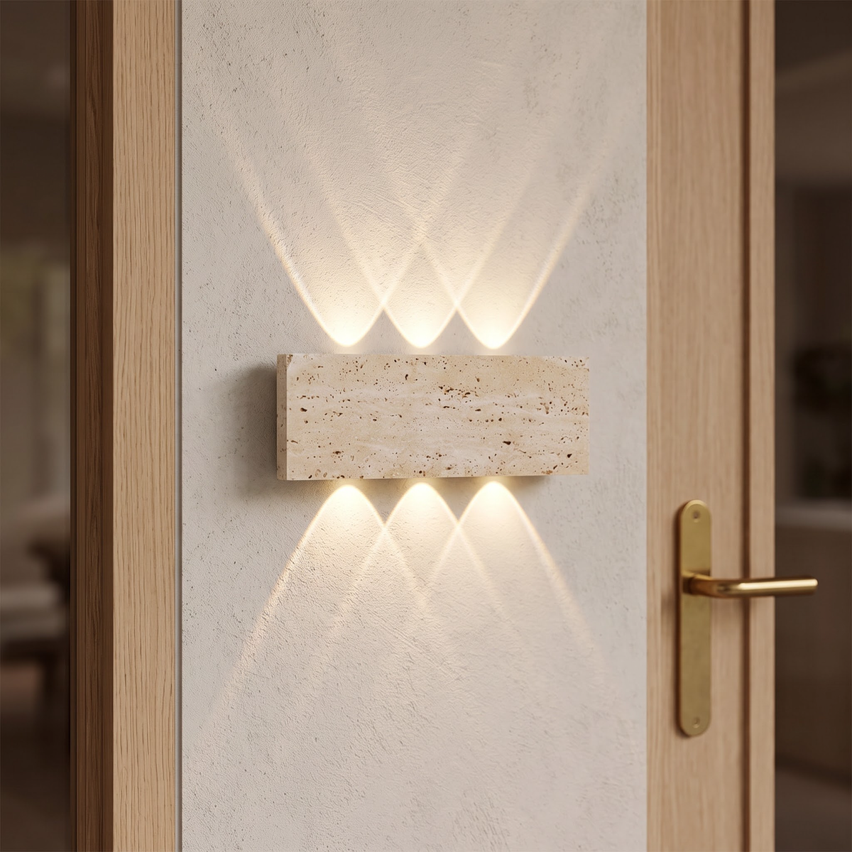 Travertine stone wall light casting fans of warm light in an entry