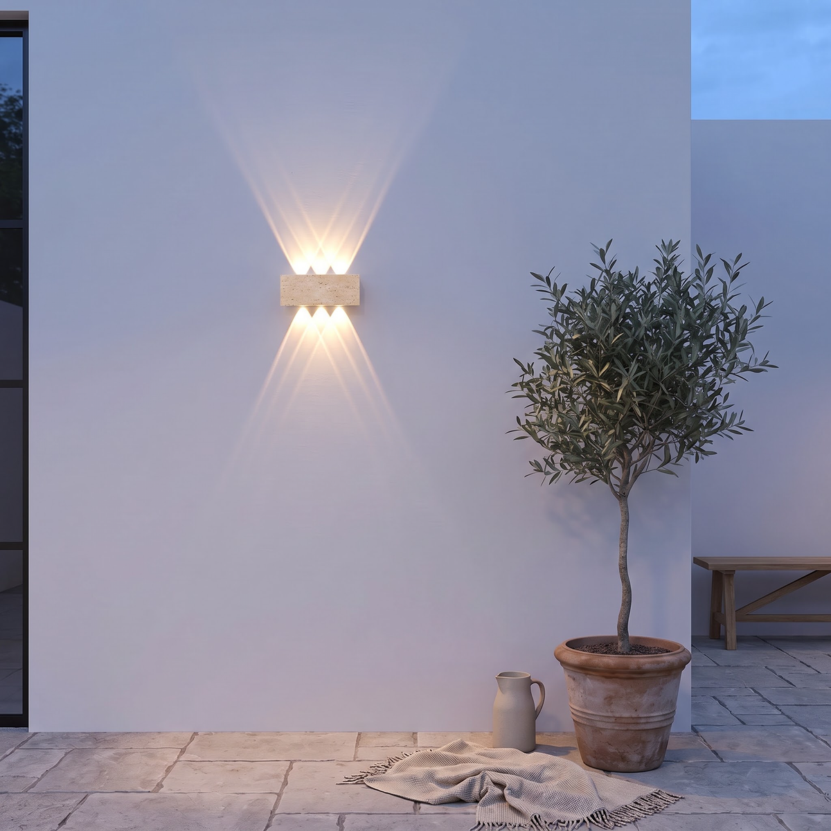 Natural stone up-down wall lamp on a courtyard wall at blue hour