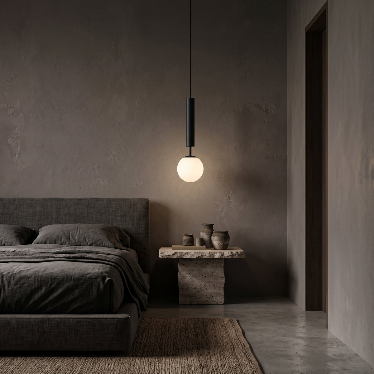 Matte black pendant light with opal glass ball above a travertine nightstand