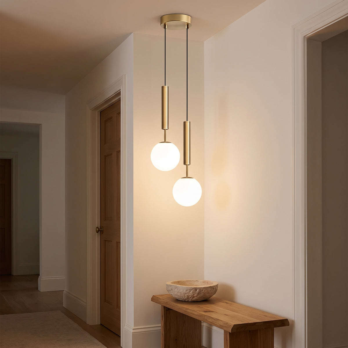 Brass double pendant light glowing above an oak bench in a hallway